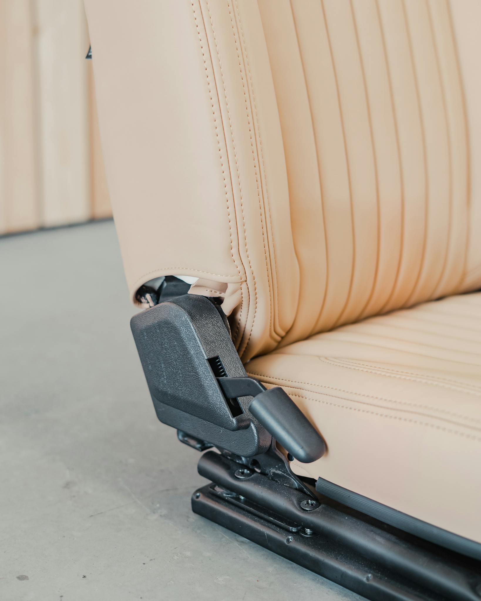 Detailed view of a beige leather car seat, smooth texture and modern design.