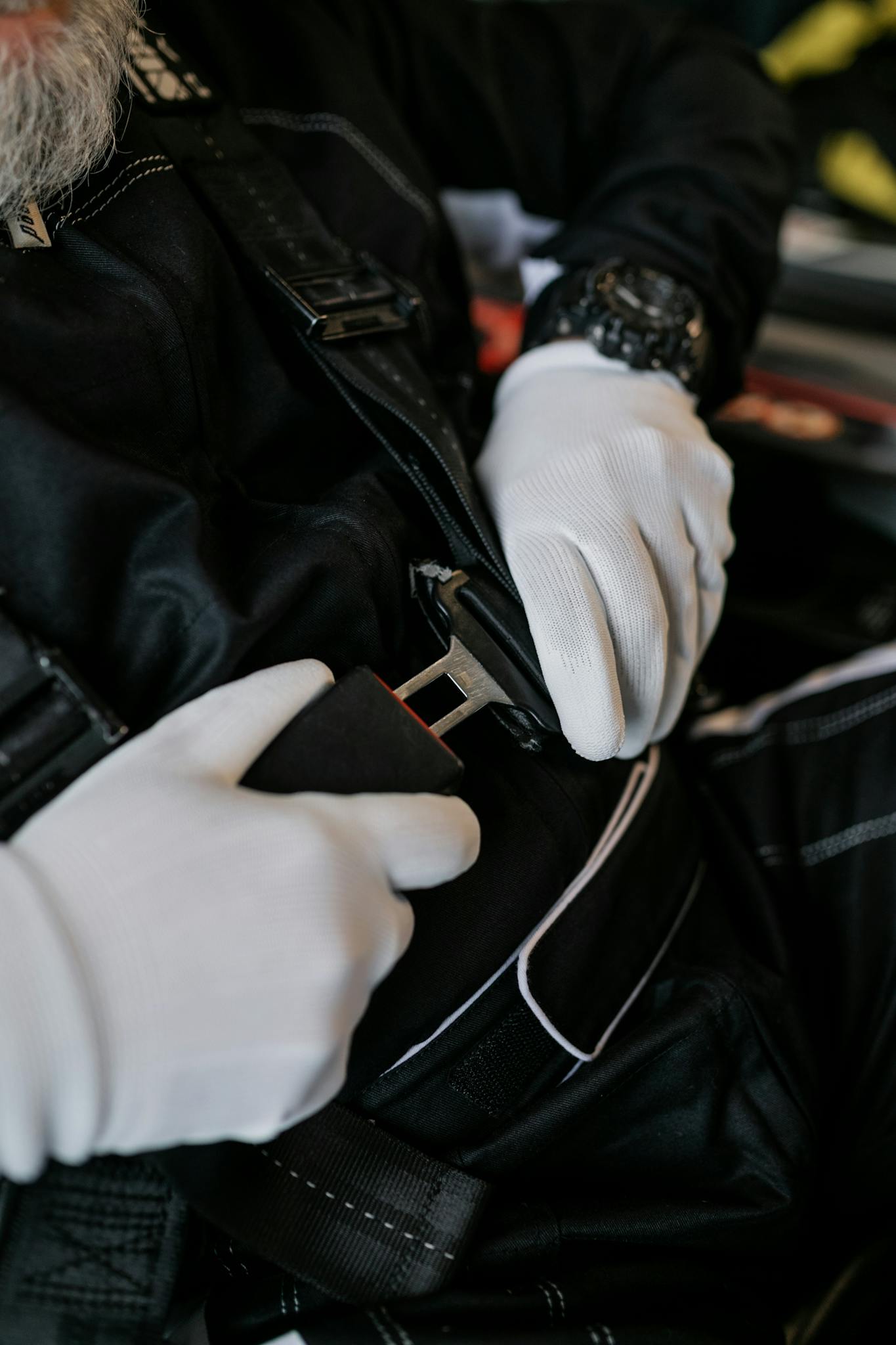 White-gloved hands fastening a seat belt in a vehicle, emphasizing safety.